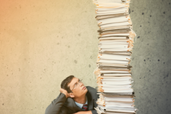 Man Looking up and Tall Piled Documents