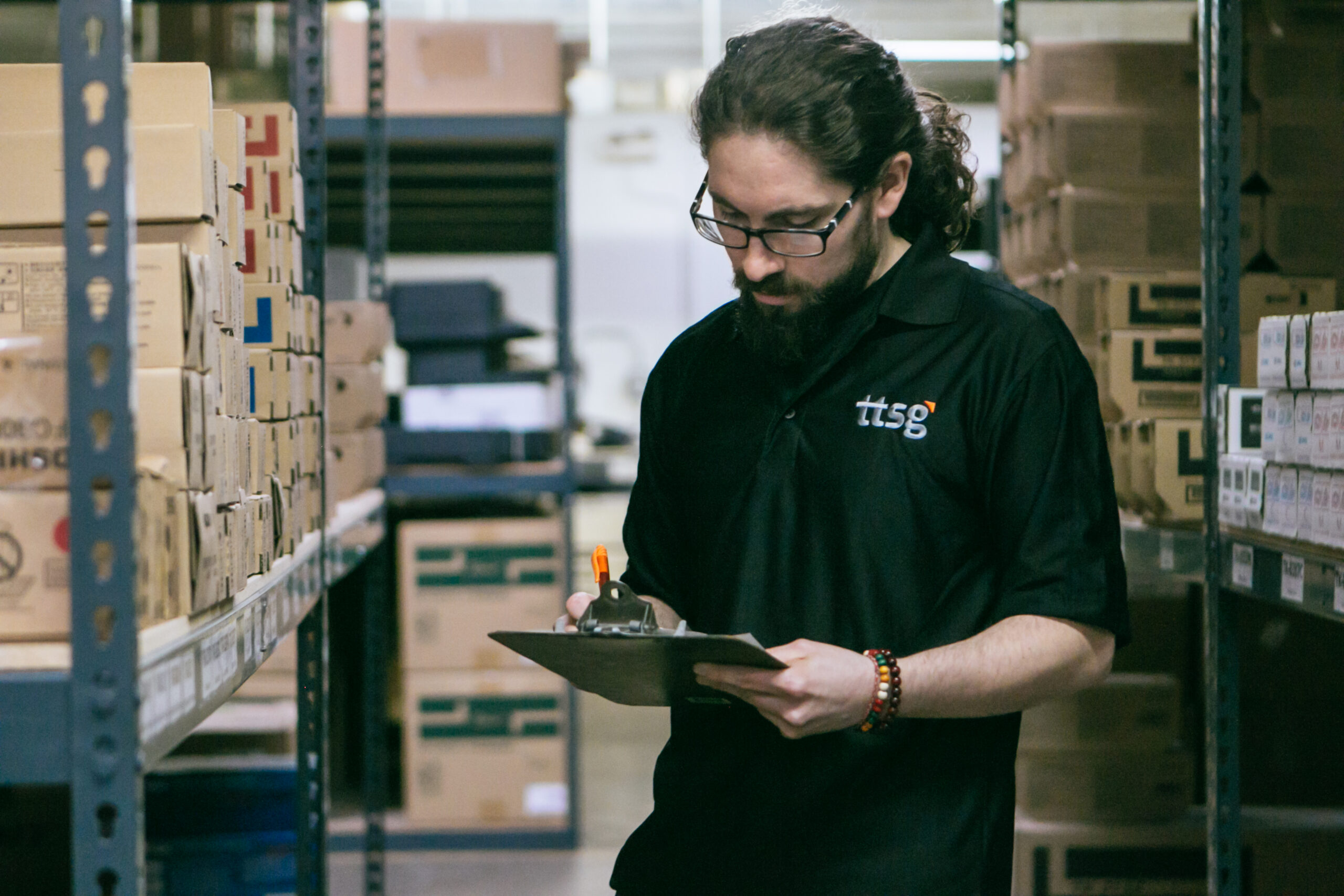 Phil 2 Phil Viverito of TTSG holding a clipboard and pen in the warehouse supply area